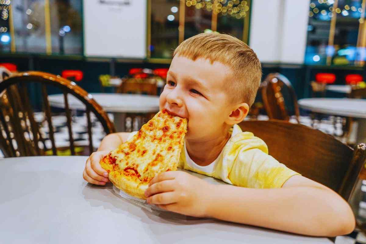 bambino che mangia una fetta di pizza