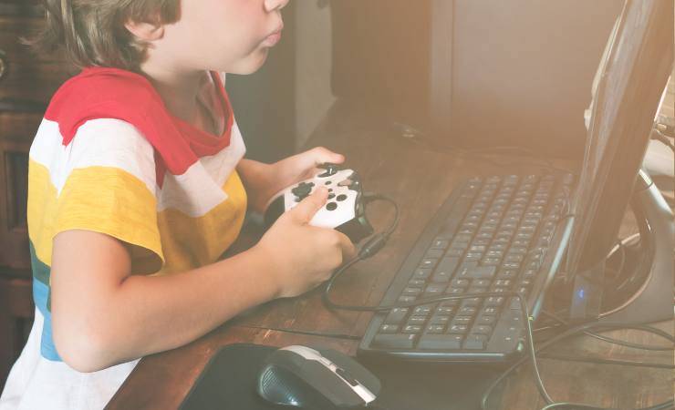 Un bambino davanti a un computer che gioca con il joystick