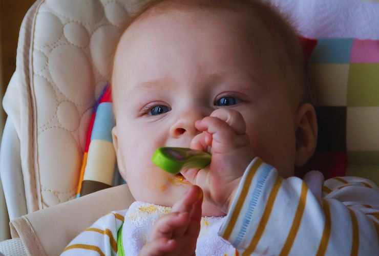 bambino mangia col cucchiaio in bocca