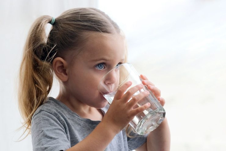 bambina che beve un bicchiere di acqua